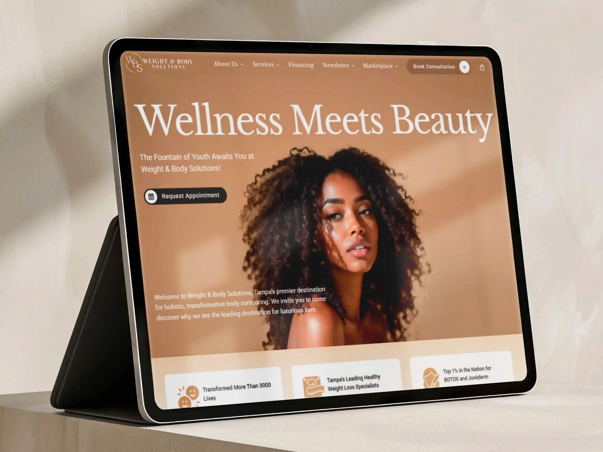 Tablet displaying a wellness website with the headline “Wellness Meets Beauty” and a portrait on a tan background