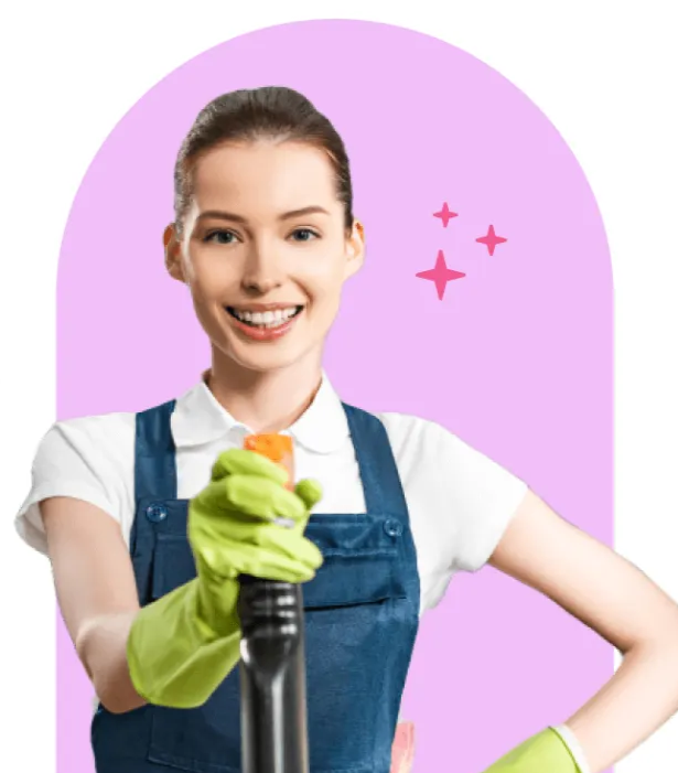Smiling cleaner in blue overalls and green gloves holding a vacuum against a pink background