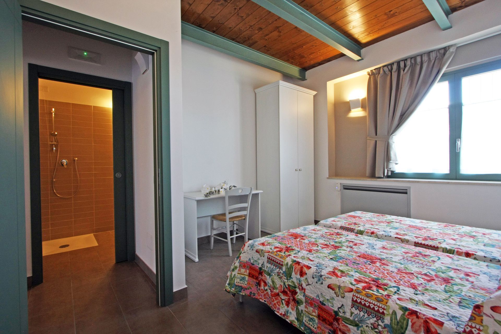 Una camera d'albergo con due letti singoli con lenzuola a fantasia floreale