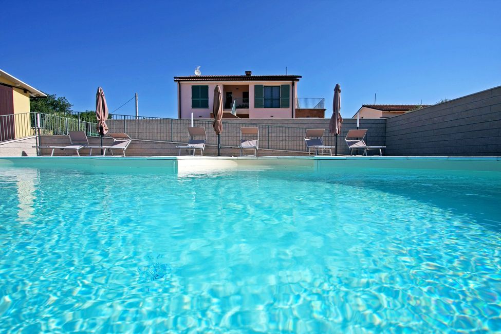 Piscina esterna circondata da paesaggio collinare.