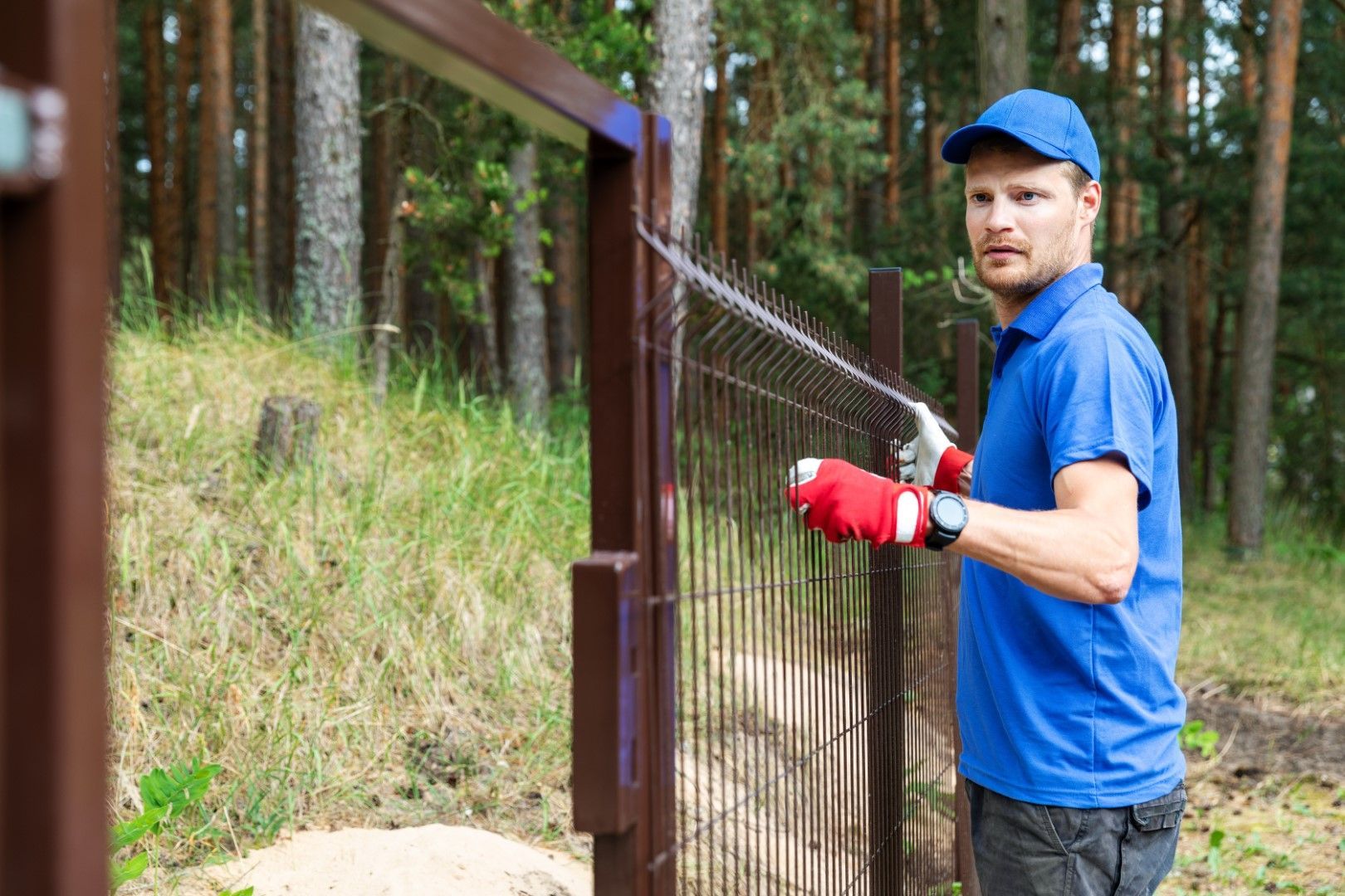 A man is painting a fence in the woods.