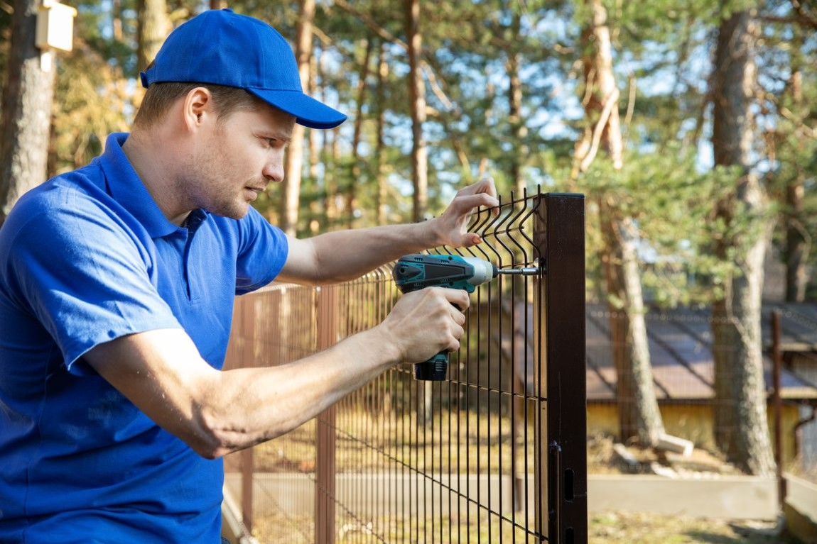 A man is installing a fence with a drill.
