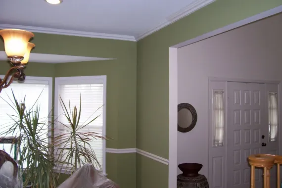 A living room with green walls and white trim