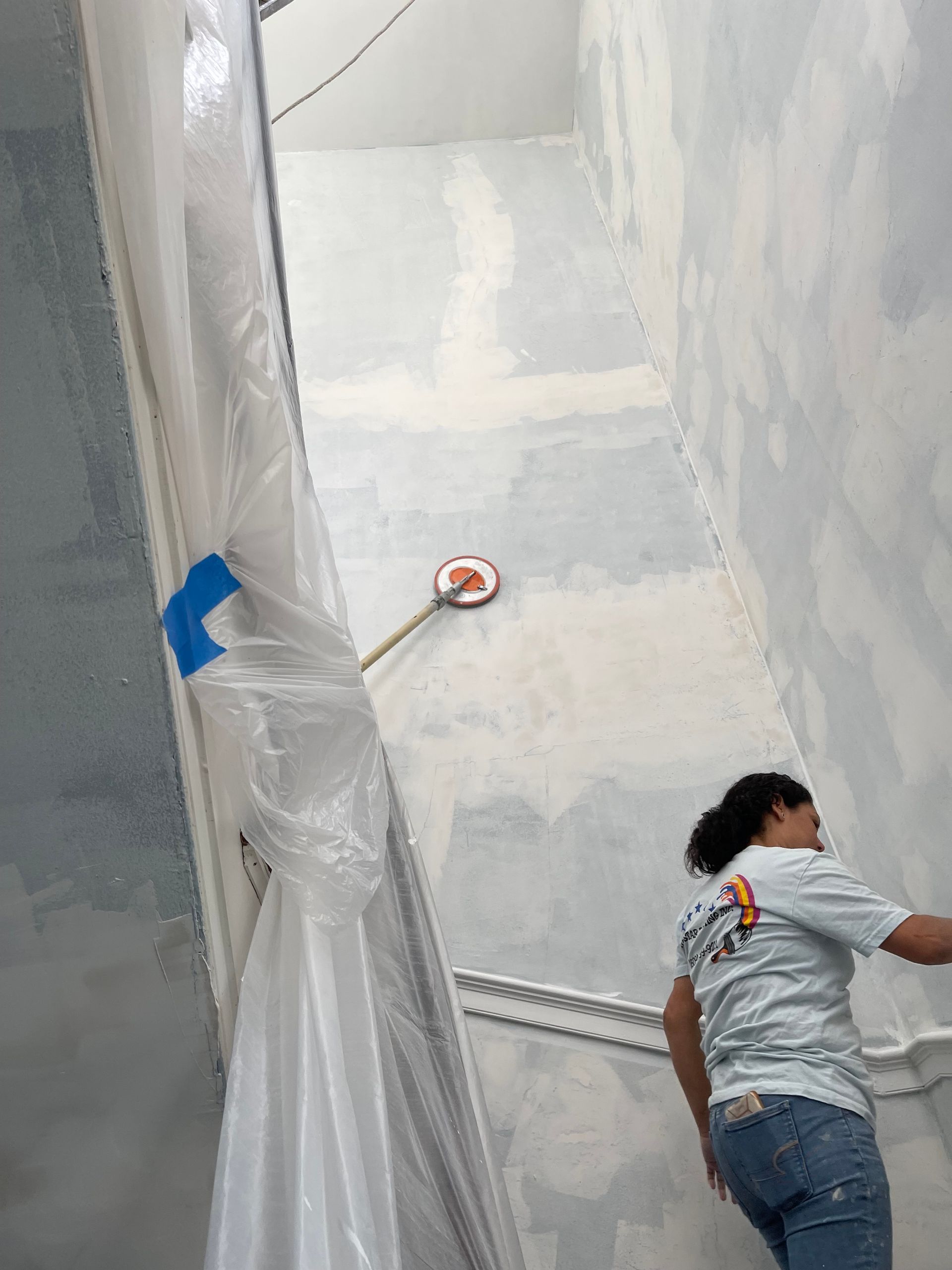 A woman is painting a wall in a room.