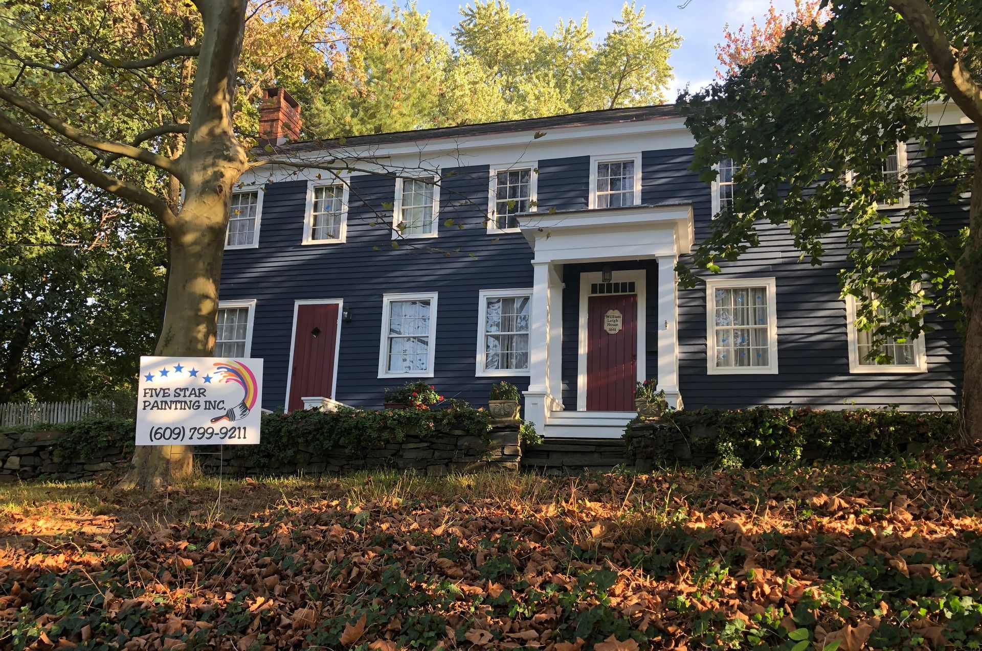 A blue house with a red door and a sign in front of it