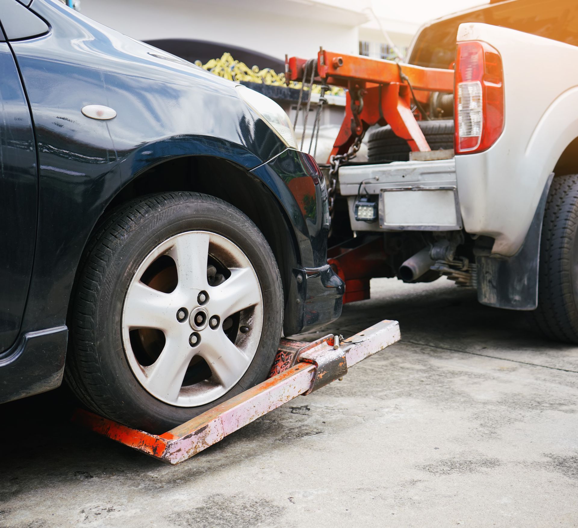 Tow truck lifting the rear of a black car after a collision with a white pickup truck Tow truck lifting the rear of a black car after a collision with a white pickup truck