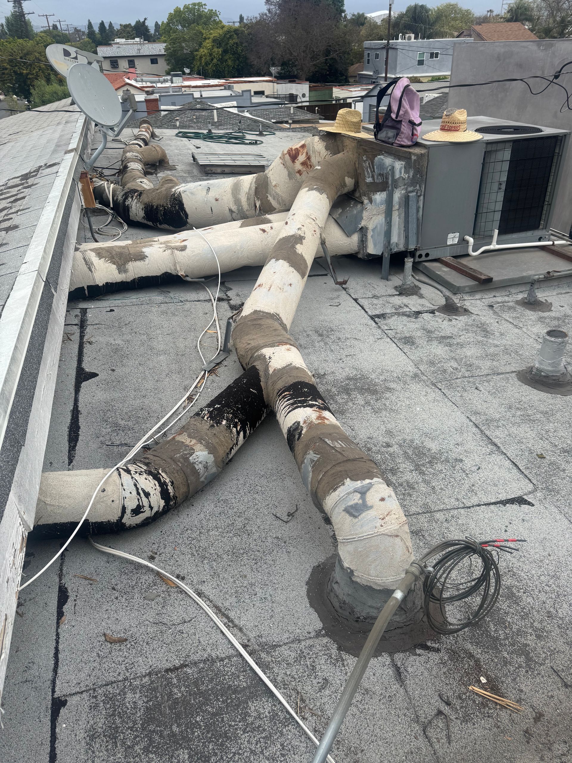 Damaged rooftop HVAC ducting with torn insulation and debris on a flat roof