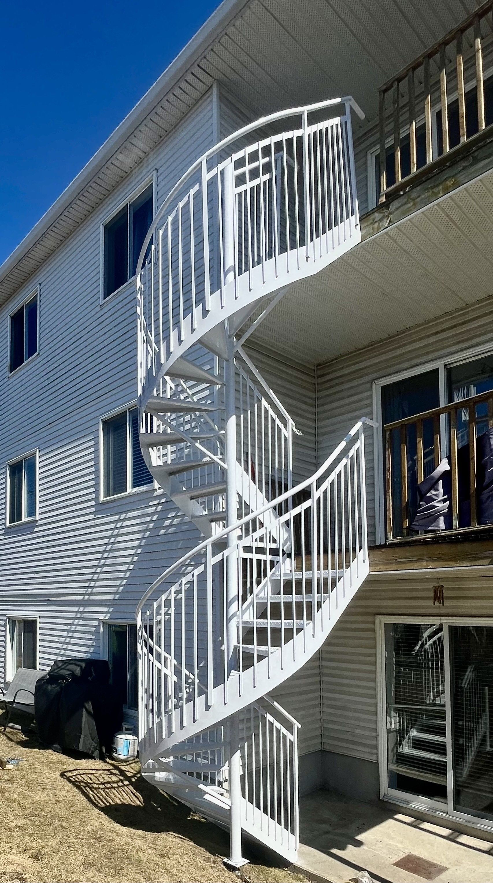 Extérieur d'un immeuble avec un escalier en colimaçon blanc. Les escaliers mènent aux balcons à chaque étage.