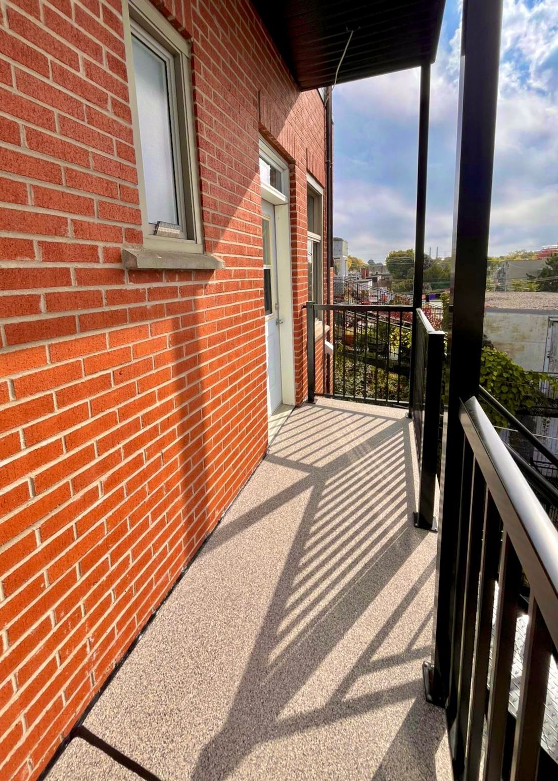 Escalier extérieur en métal menant à une porte grise sur un bâtiment en briques.
