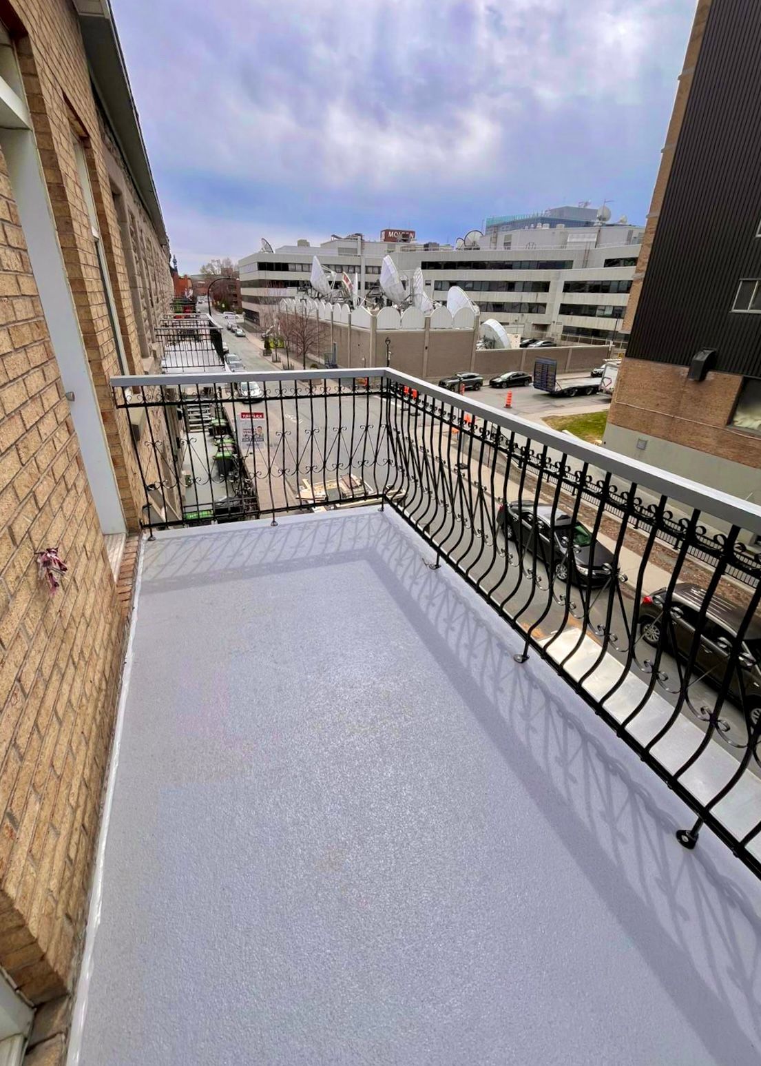 Vue extérieure d'un escalier en métal noir sur un bâtiment en briques ; marches et rampe en bois.