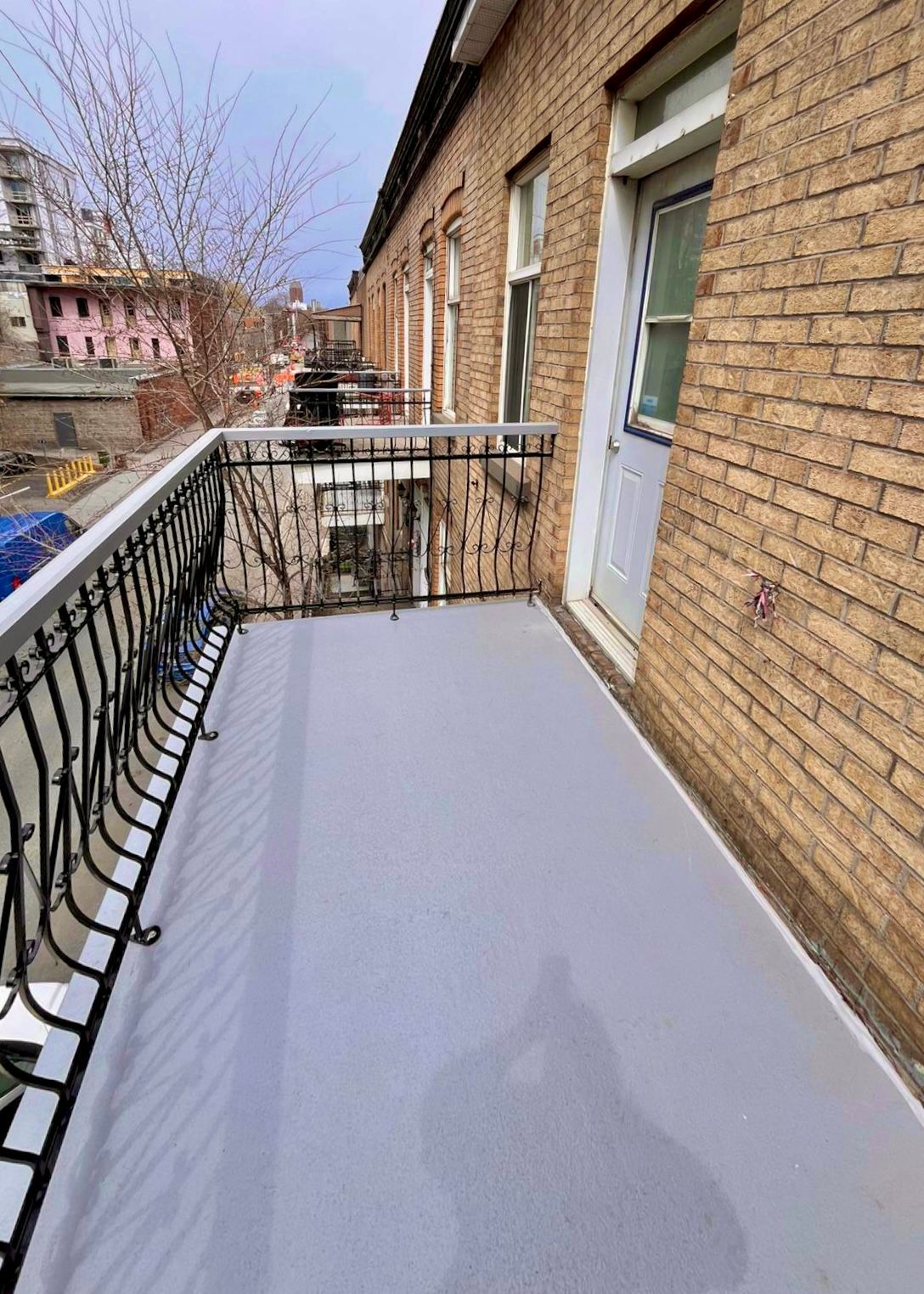 Extérieur d'un bâtiment en briques avec escaliers extérieurs, rampes noires et portes.