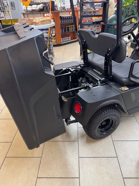 Black utility cart with lifted cargo bed, parked inside a store, showing the vehicle's mechanics and a red tail light.