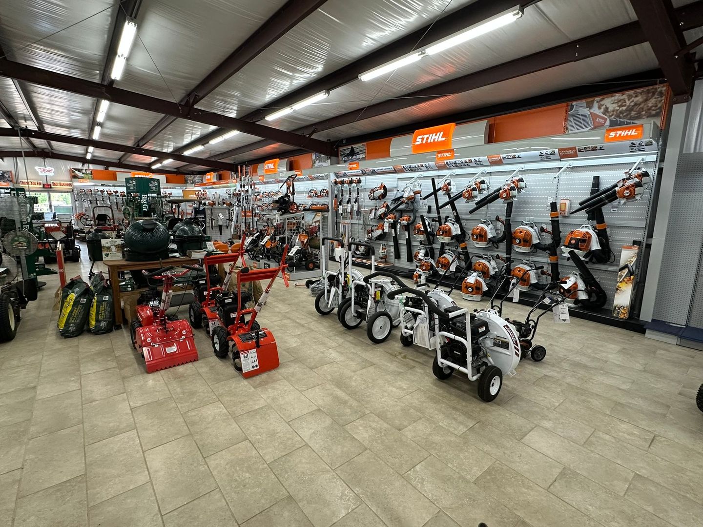 Inside a hardware store, various lawn care tools on display, under bright lights.