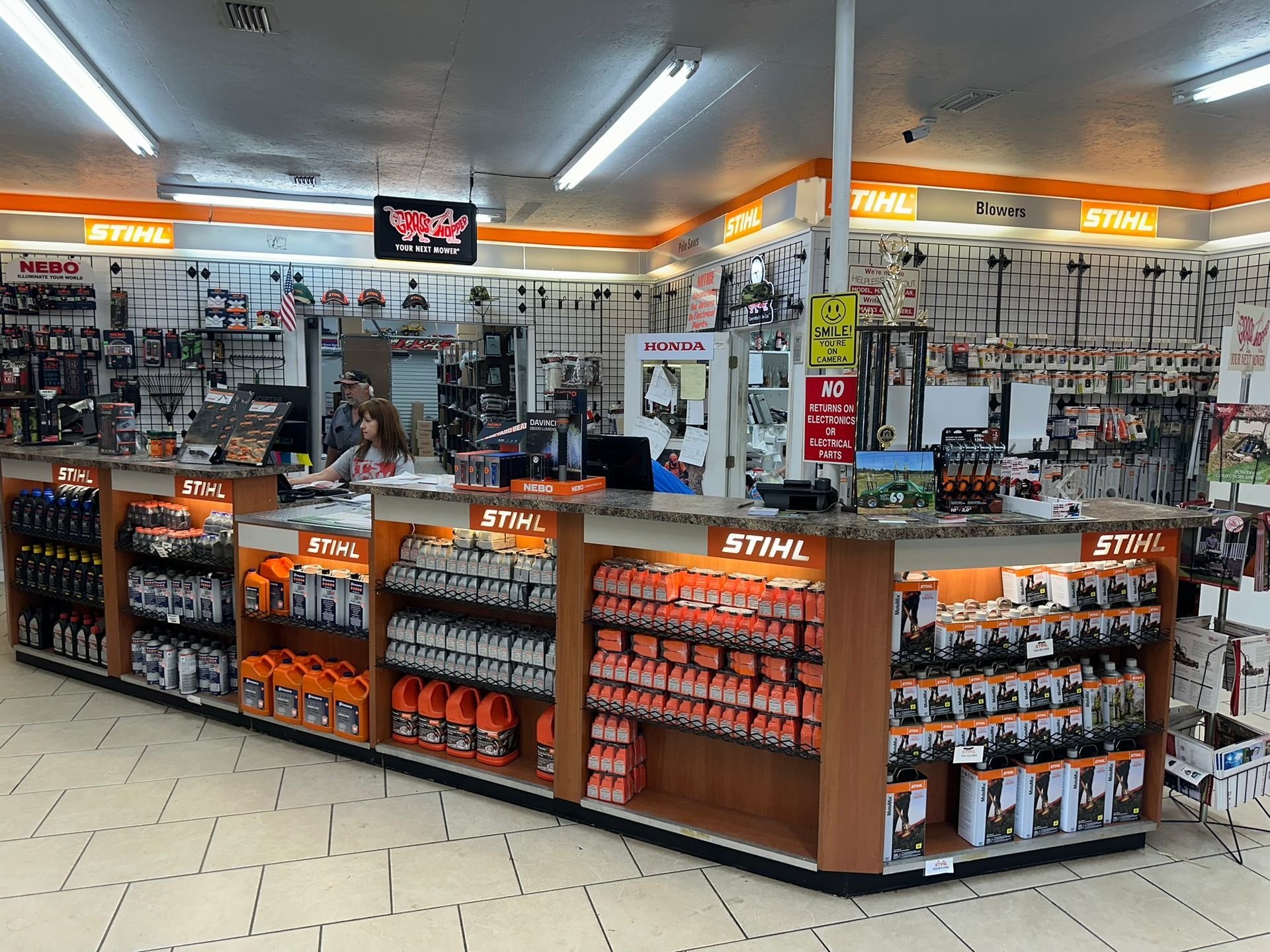 Inside a Stihl store, merchandise displayed behind a long counter. Orange and black product packaging prominent.