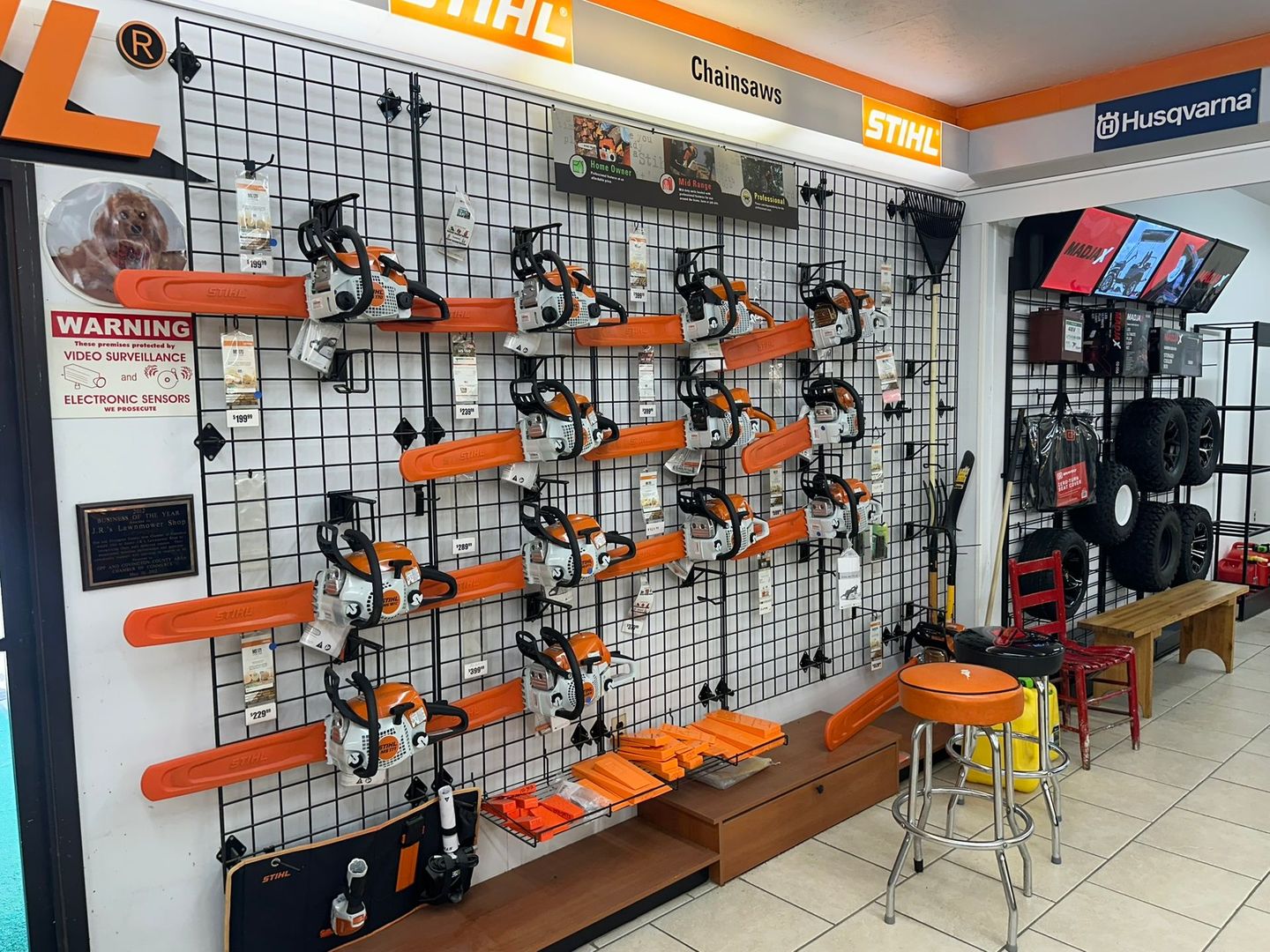 Chainsaws displayed on a grid wall in a store, with orange and white colors prominent.