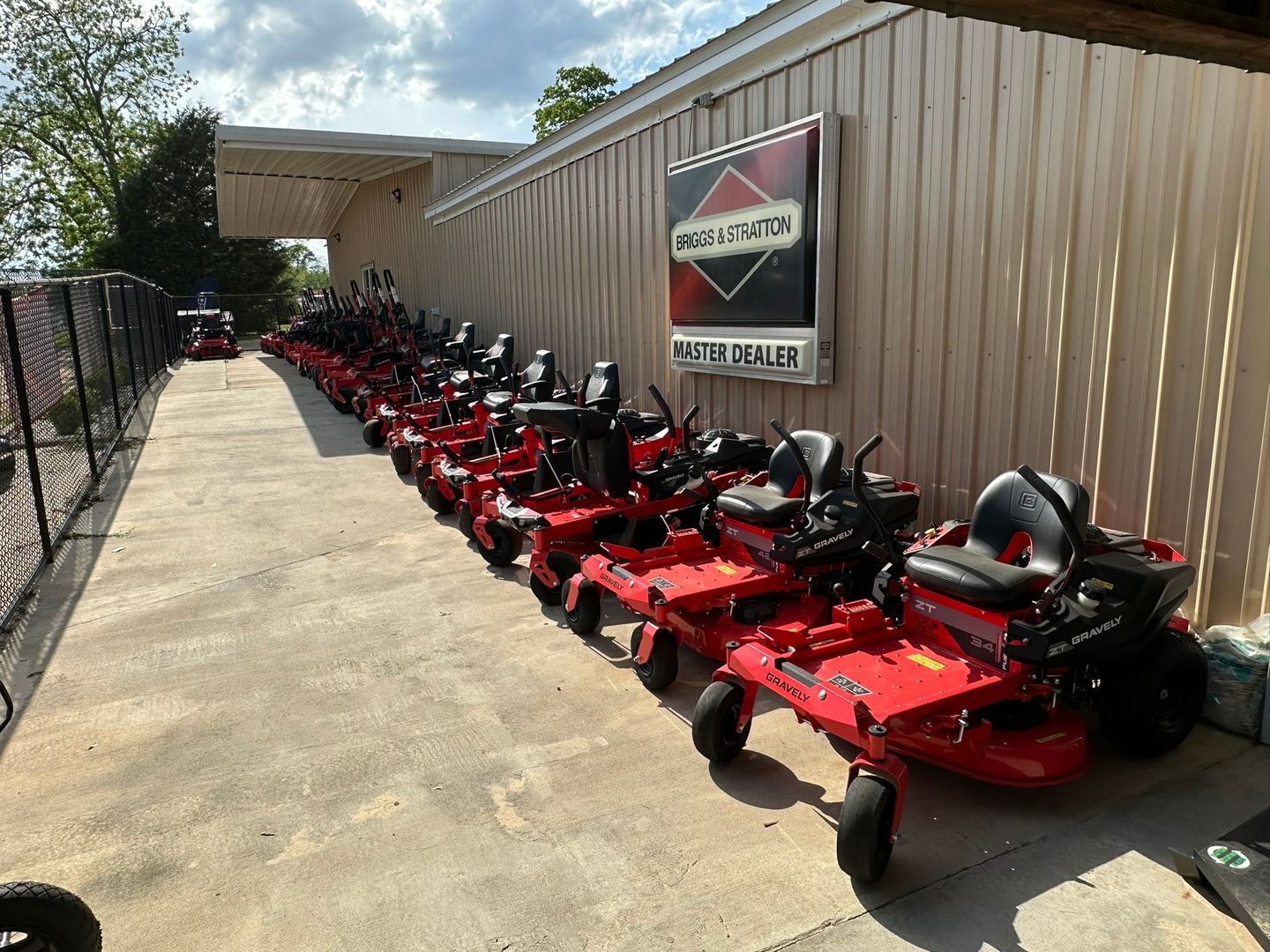 Row of red zero-turn mowers for sale outside a building with a Briggs & Stratton sign.