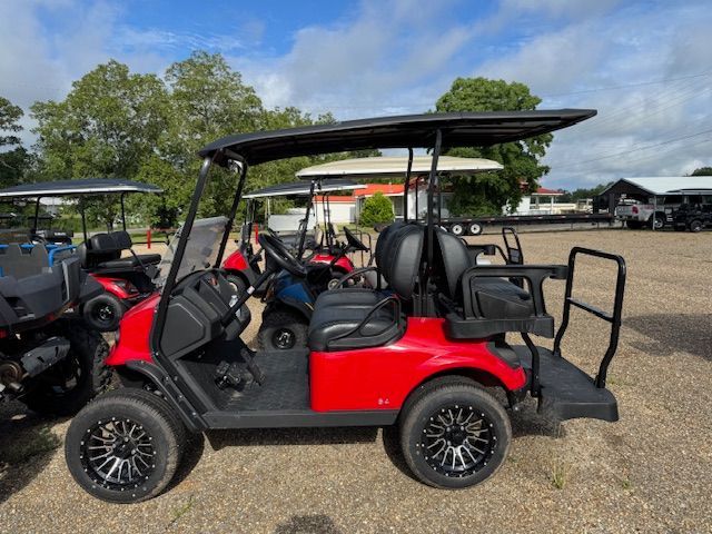 Red golf cart with black accents, parked outdoors, under a blue sky.