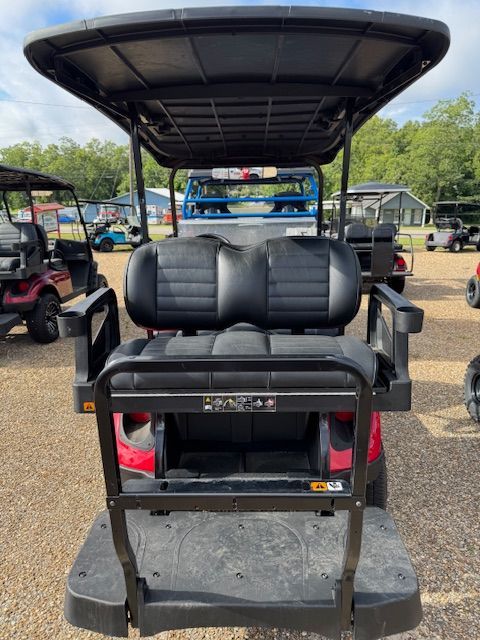 Red golf cart with black accents, parked outdoors, under a blue sky.
