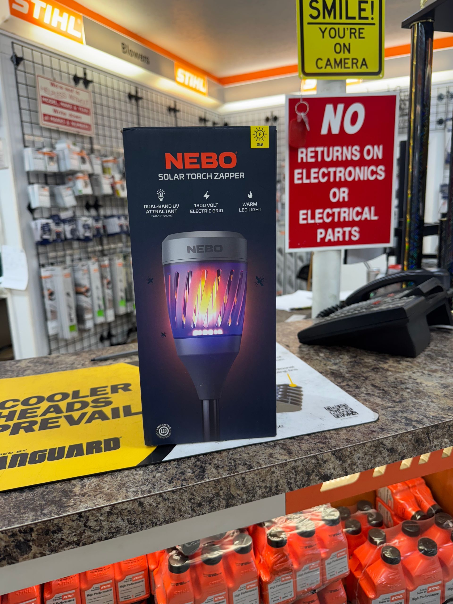 A product box for a NEBO solar torch, near a cash register with a 