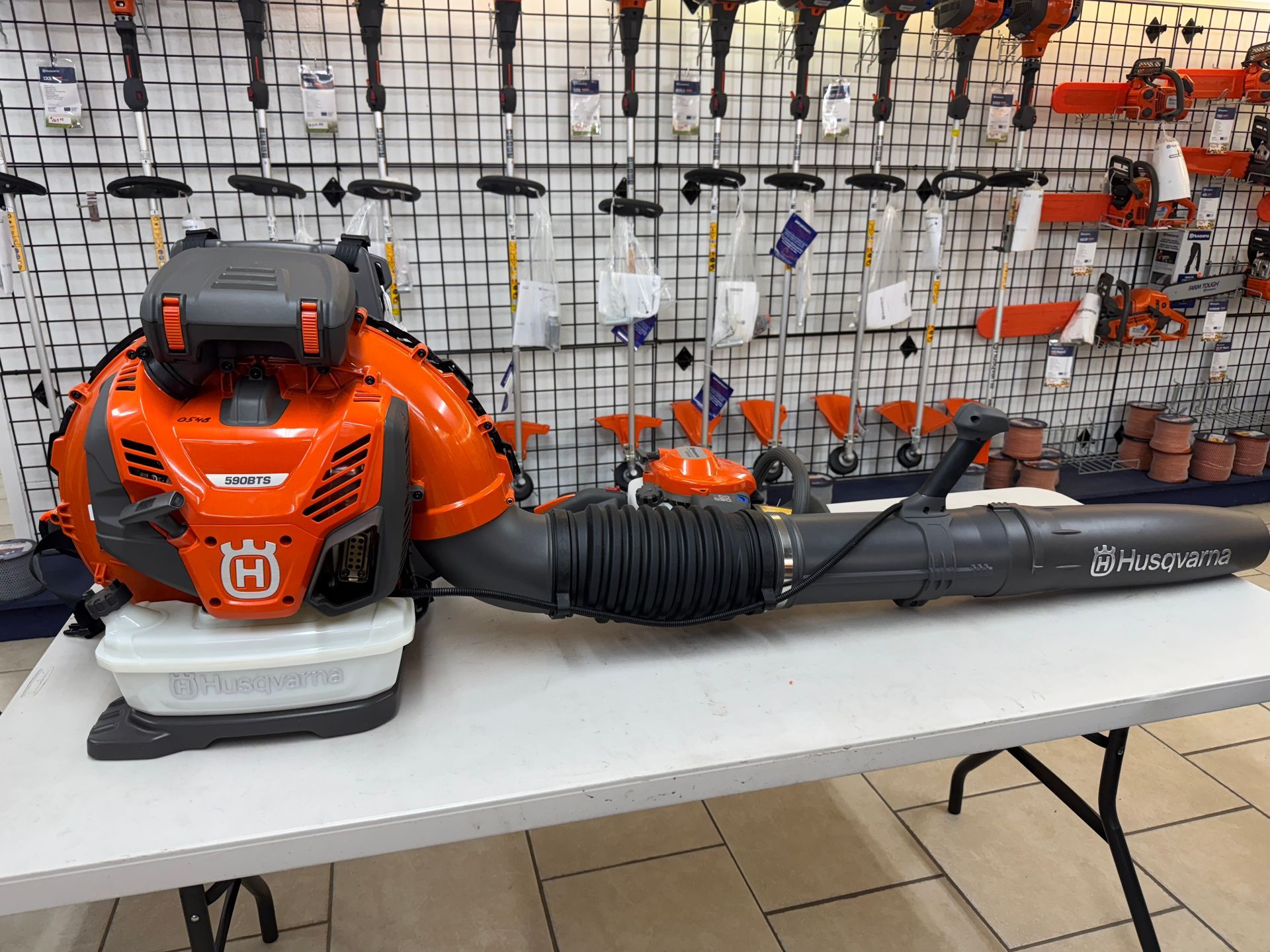 Orange Husqvarna backpack leaf blower on a table in a store.