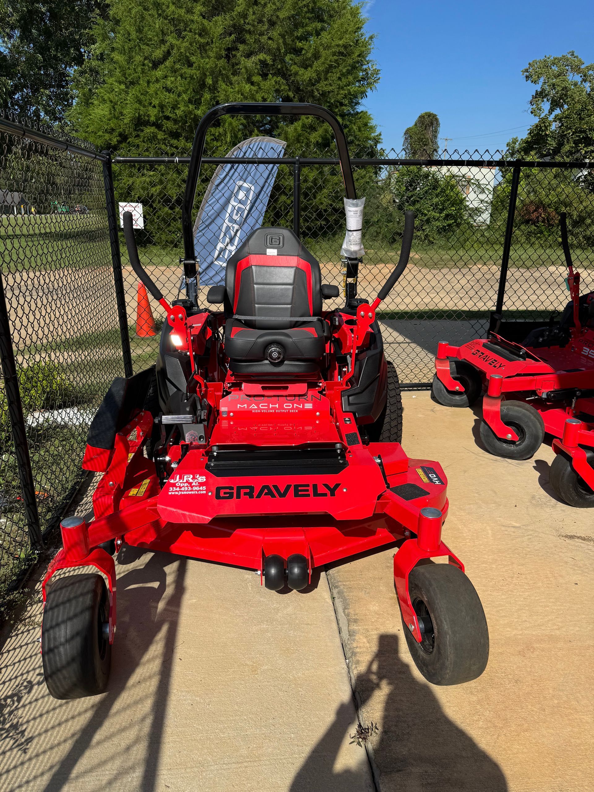 Red Gravely zero-turn lawn mower on a concrete pad, ready for use, with another mower visible in the background.