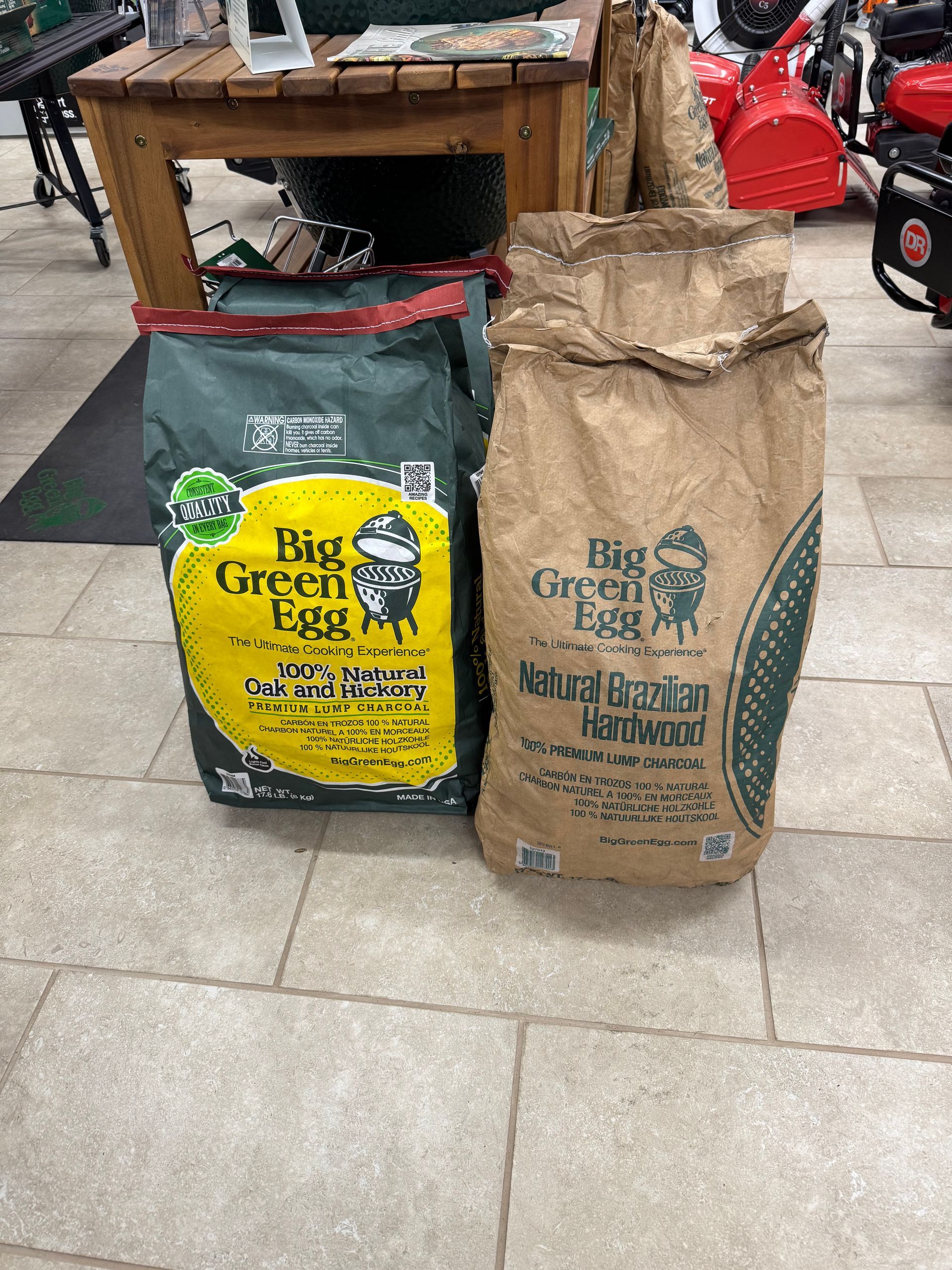 Two bags of Big Green Egg charcoal: oak & hickory in green bag, and natural brazilian hardwood in brown.