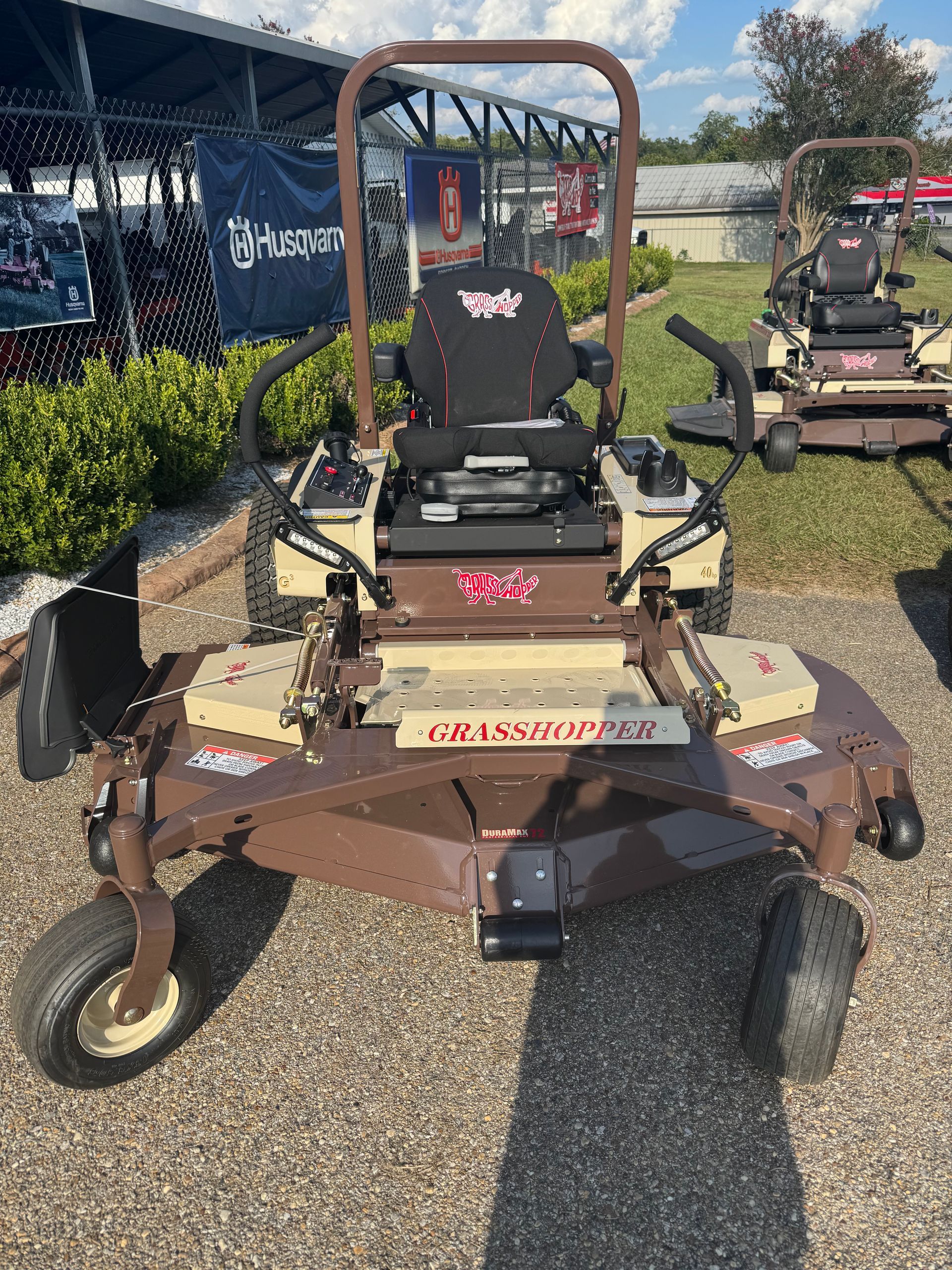 Brown and tan Grasshopper zero-turn lawn mower on display, outdoor setting.