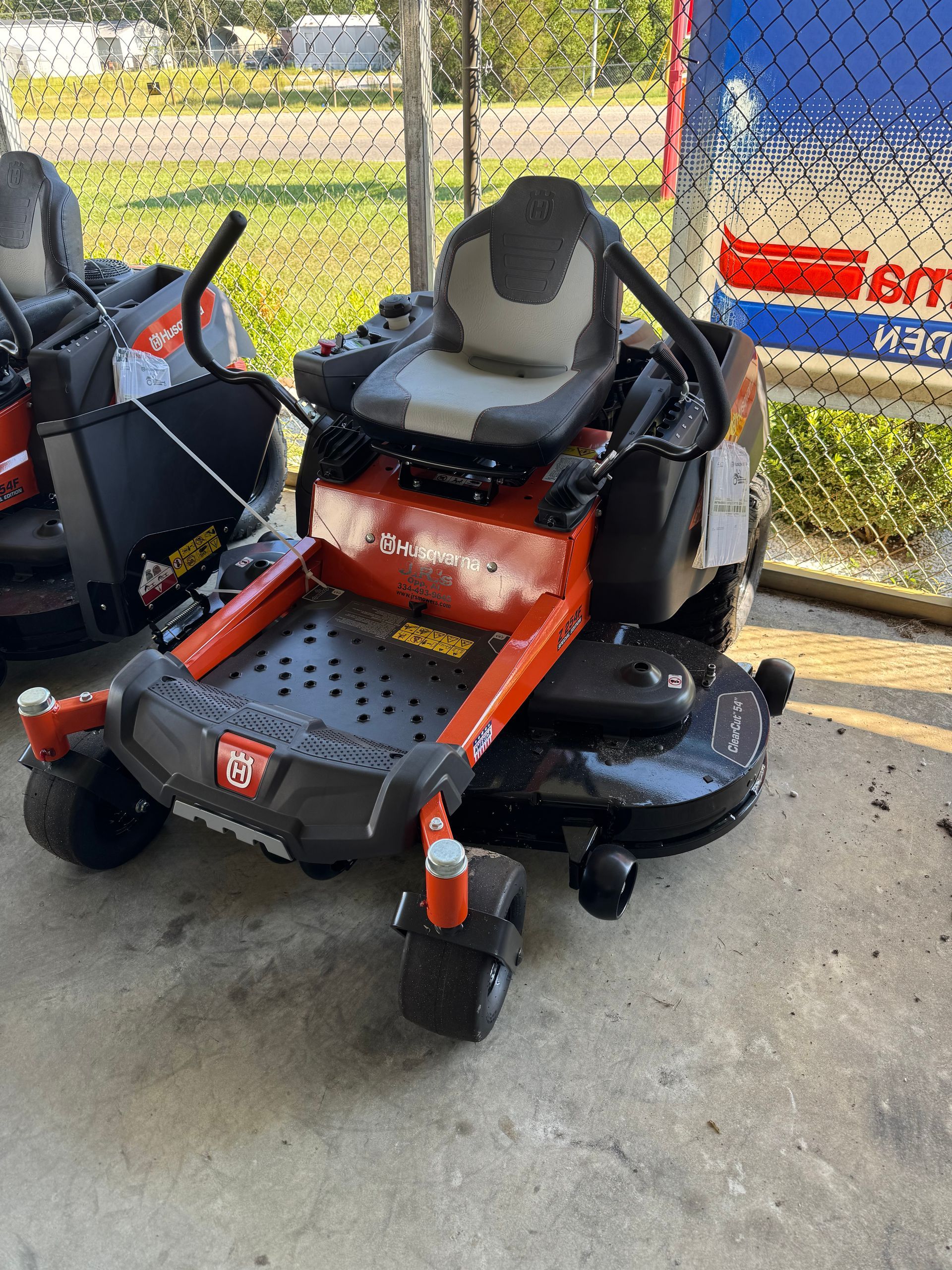 Red and black zero-turn lawn mower on a concrete surface, ready for use.