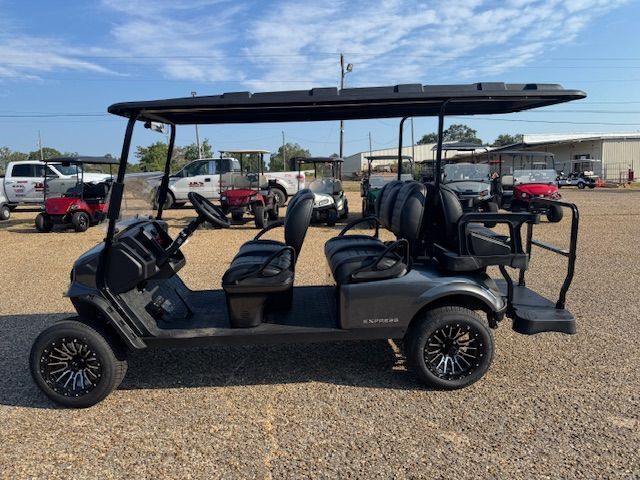 Gray golf cart with black roof and wheels parked outdoors.