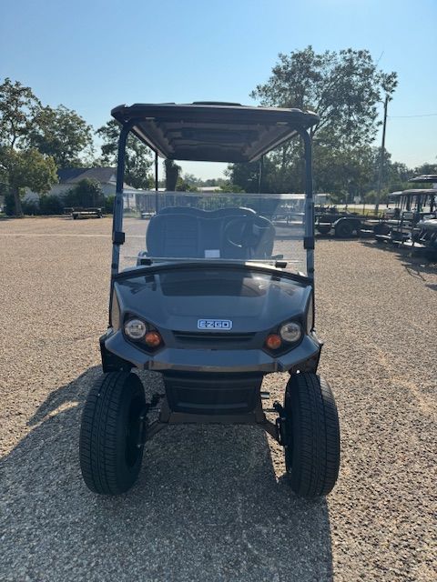Gray golf cart with black roof and wheels parked outdoors.