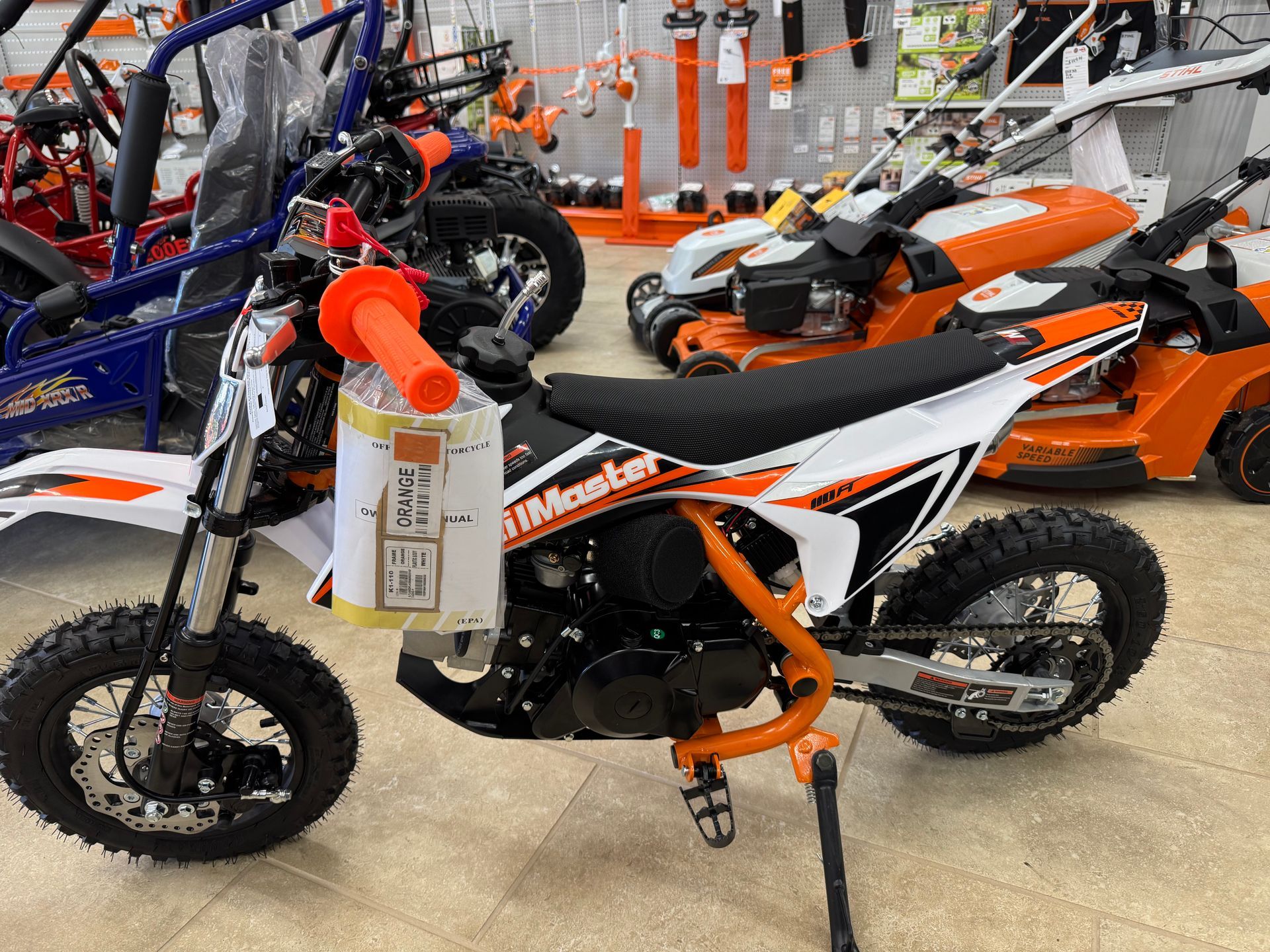 White and orange dirt bike with a price tag, in a store.