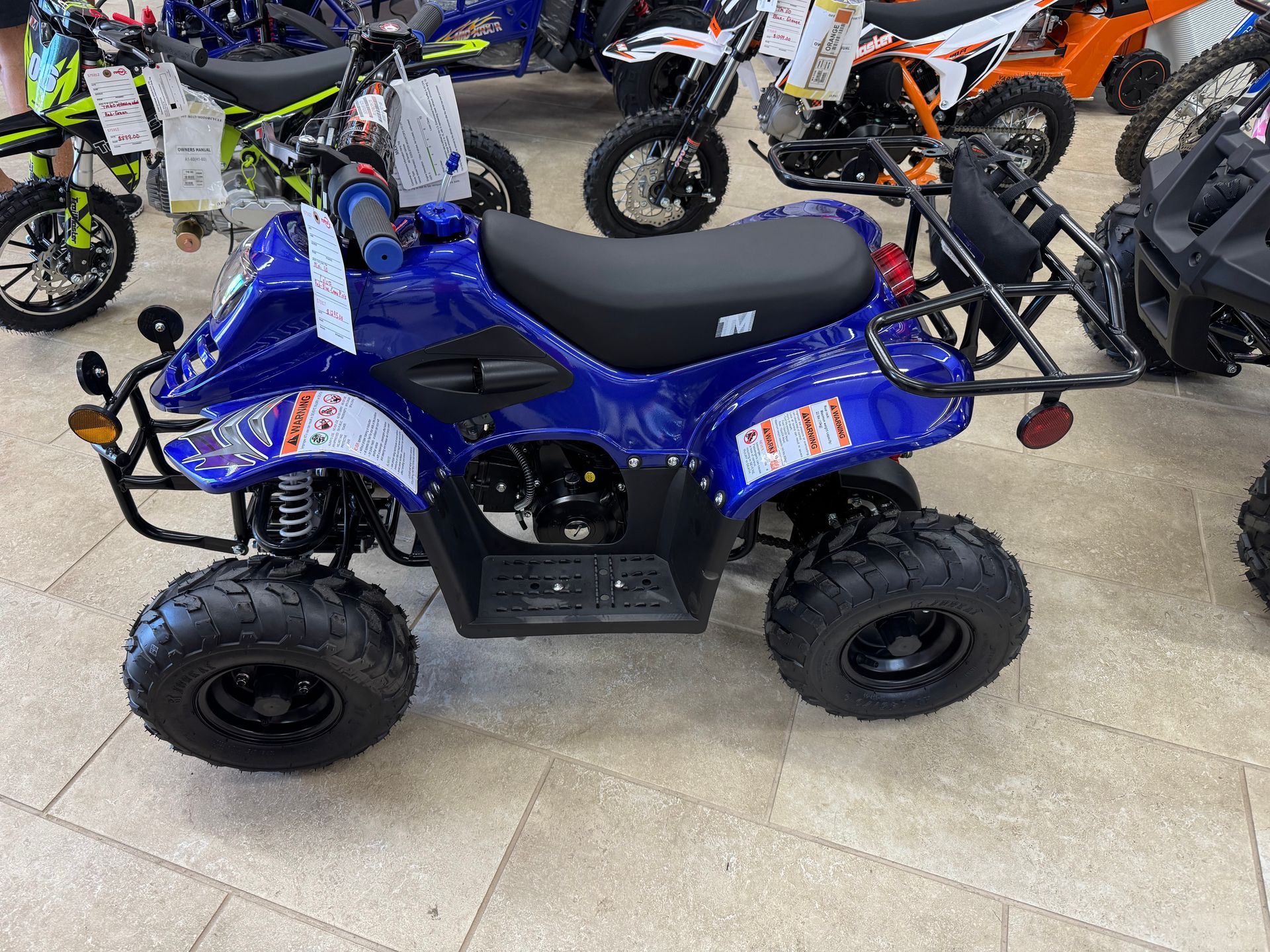Blue ATV for sale in a store, with black wheels and seat.