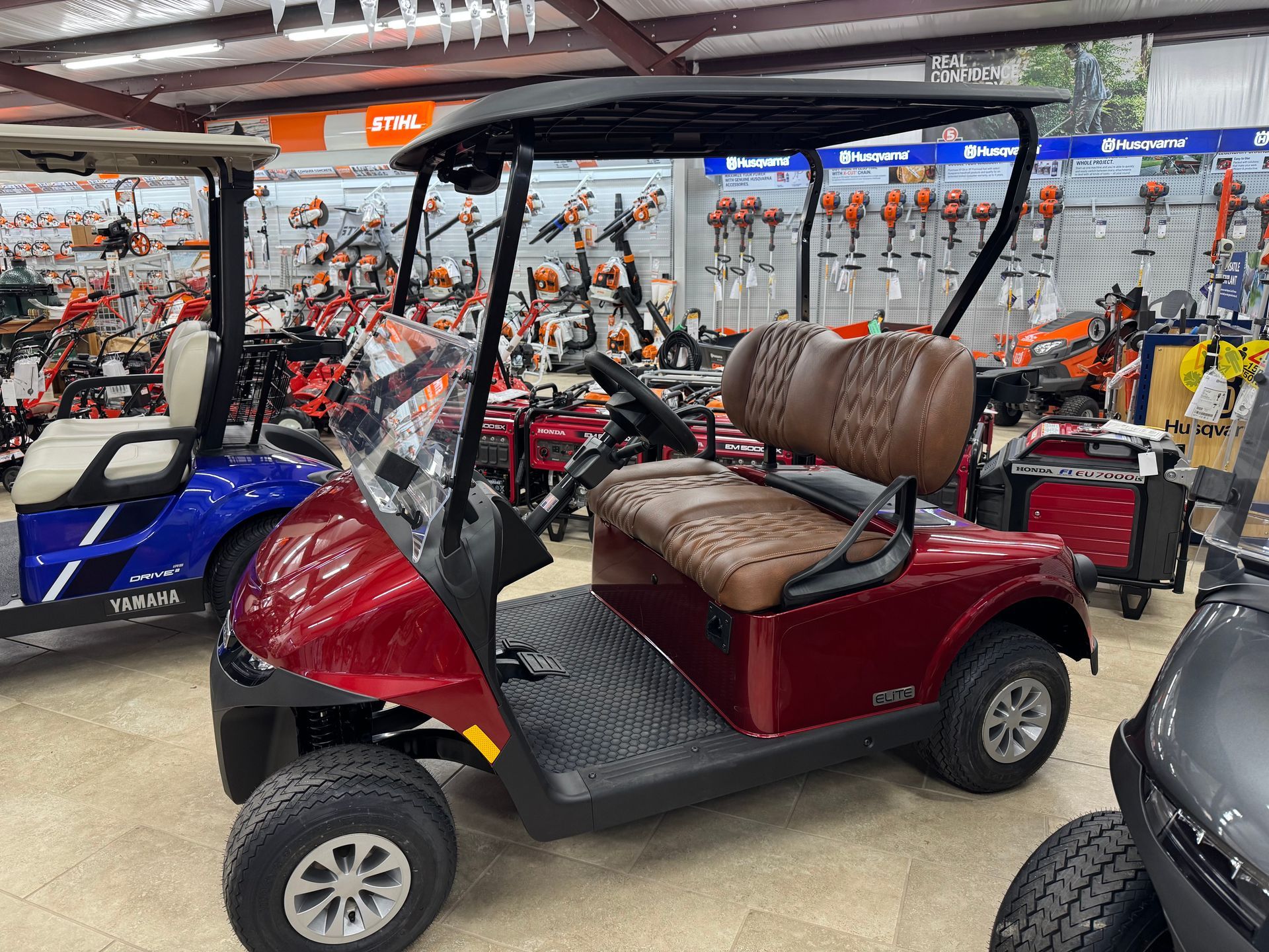 Red golf cart with brown seats, parked indoors.