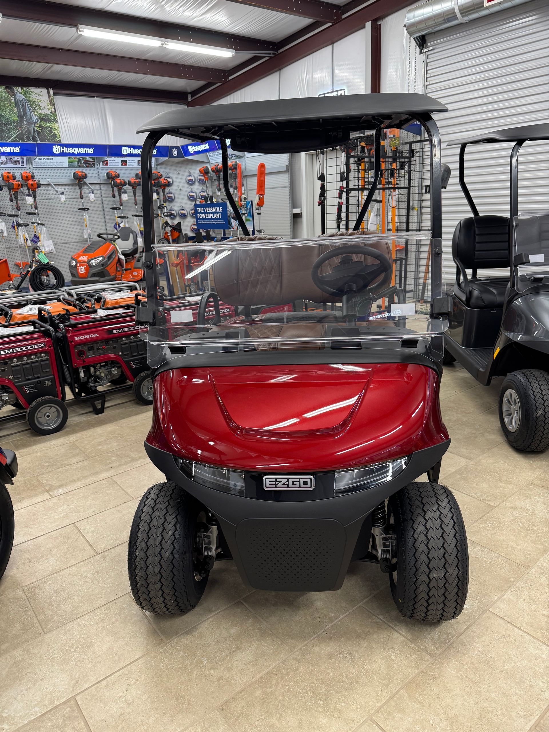 Red golf cart with brown seats, parked indoors.