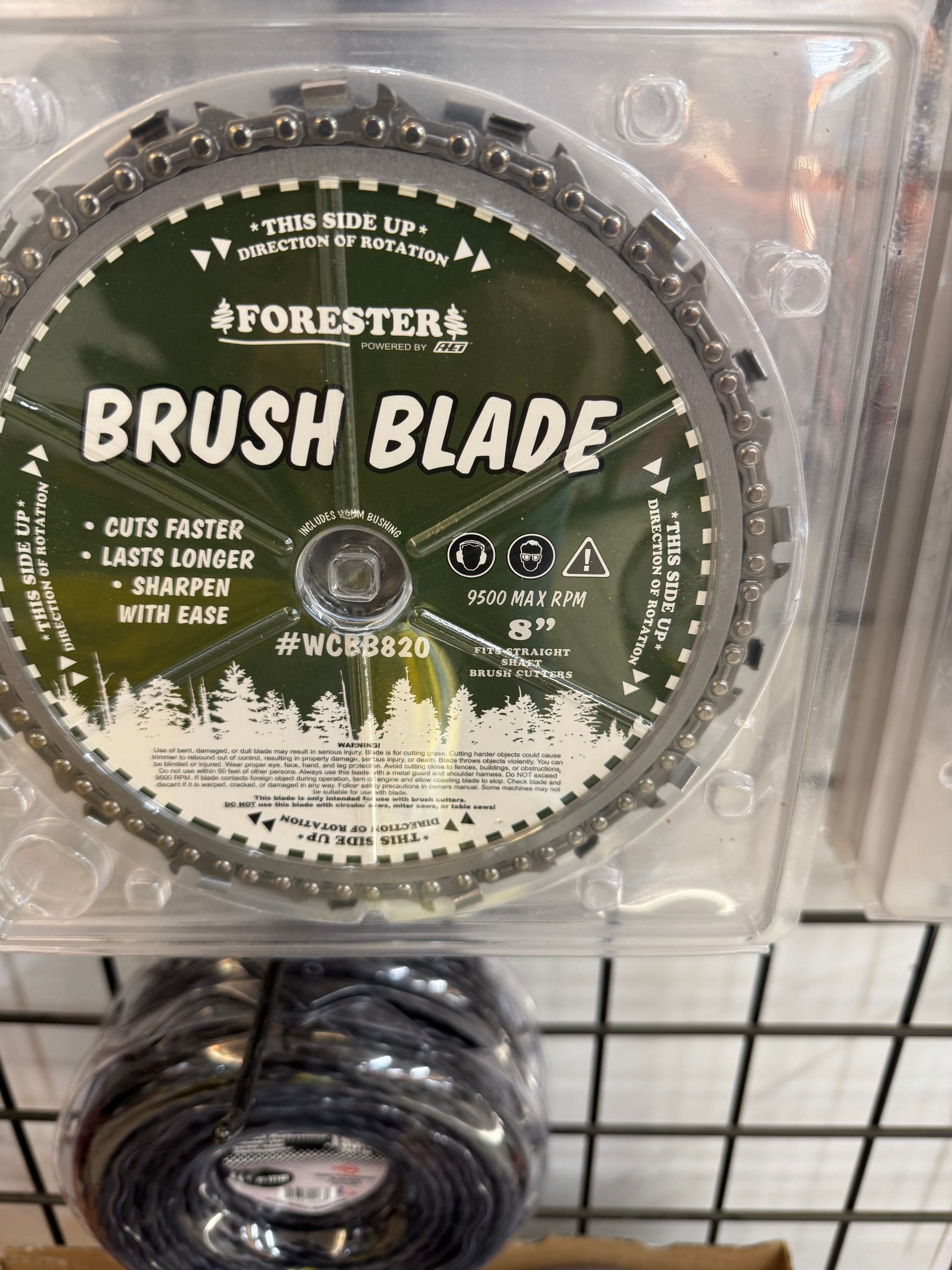 Forester brush blade in packaging; green and white label, metal blade with teeth, below a spool of black string.