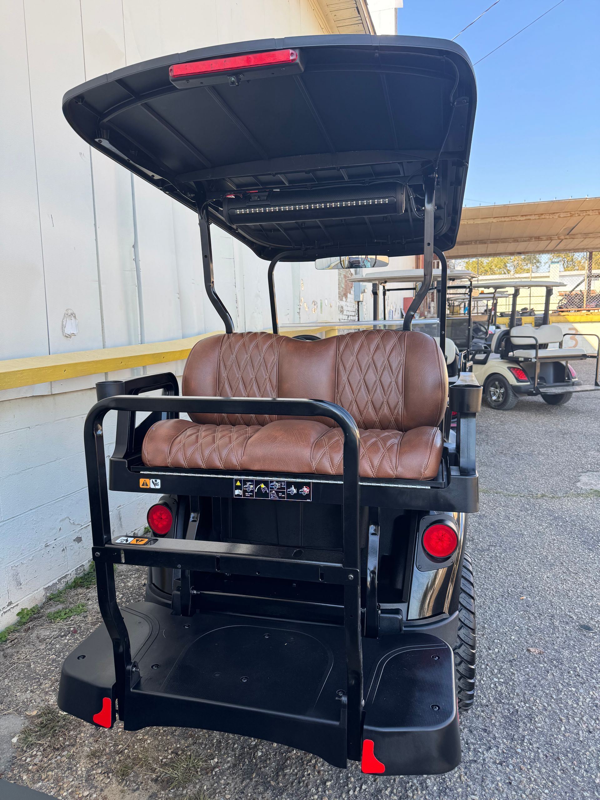 Black golf cart with clear windshield and black roof, parked outdoors.