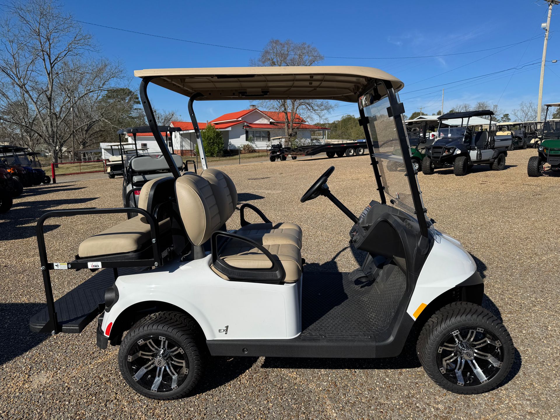 White golf cart with tan roof and seats on a paved lot on a sunny day.