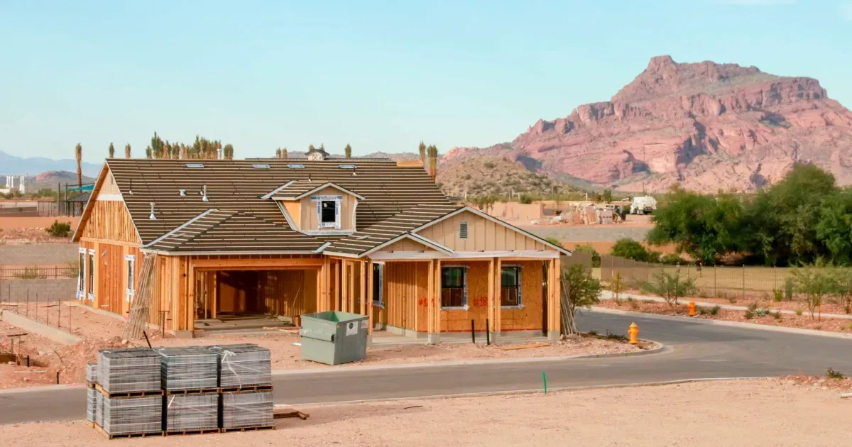 House under construction in desert setting, mountain background.