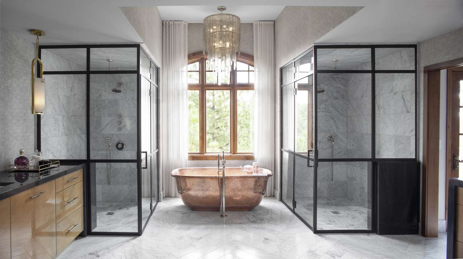 Luxurious bathroom with copper tub, marble floors, glass showers, and a chandelier.