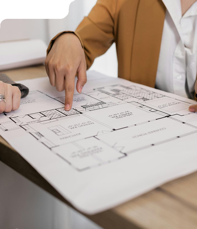 Person pointing at a house blueprint, discussing the floor plan at a desk.