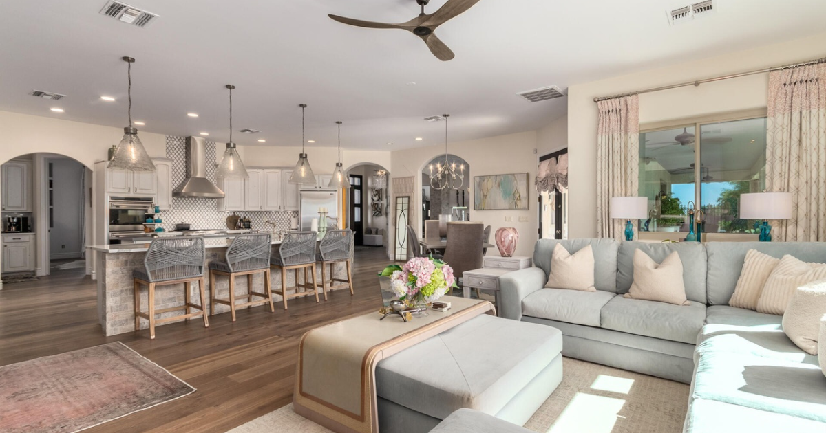 Open-concept living space with kitchen, living room. Blue and neutral tones, modern design, ample natural light.