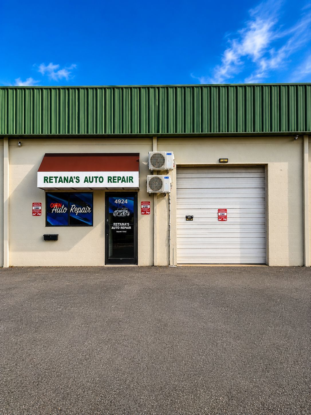 Two-story auto repair shop with green roof and white garage door under a blue sky | Retana's Auto Repair LLC