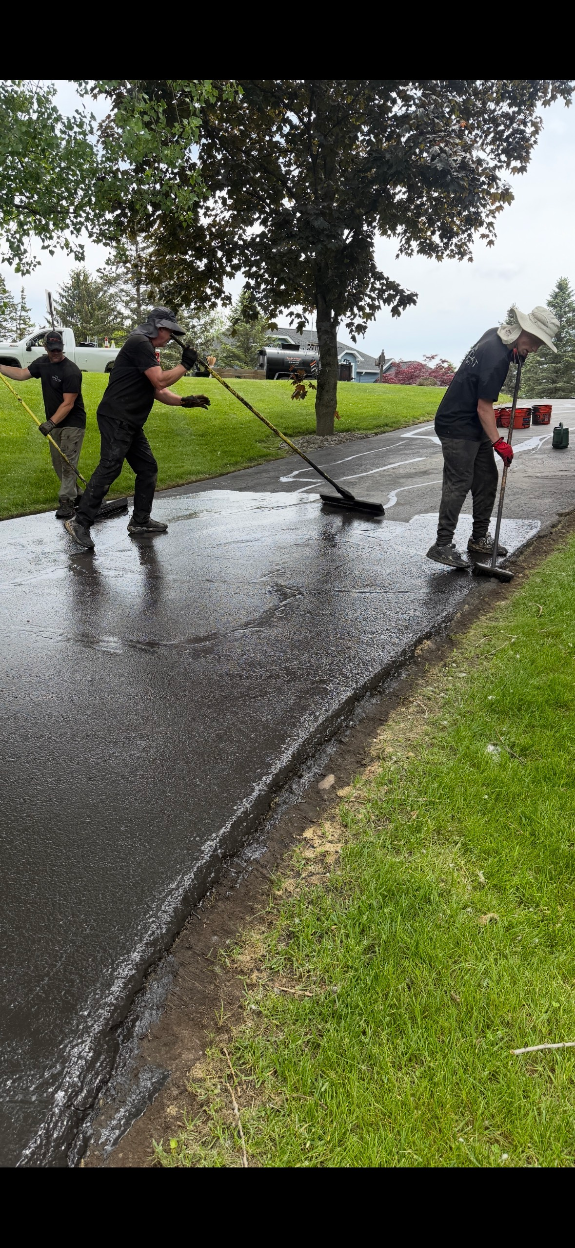 A group of people are cleaning a sidewalk in the rain.