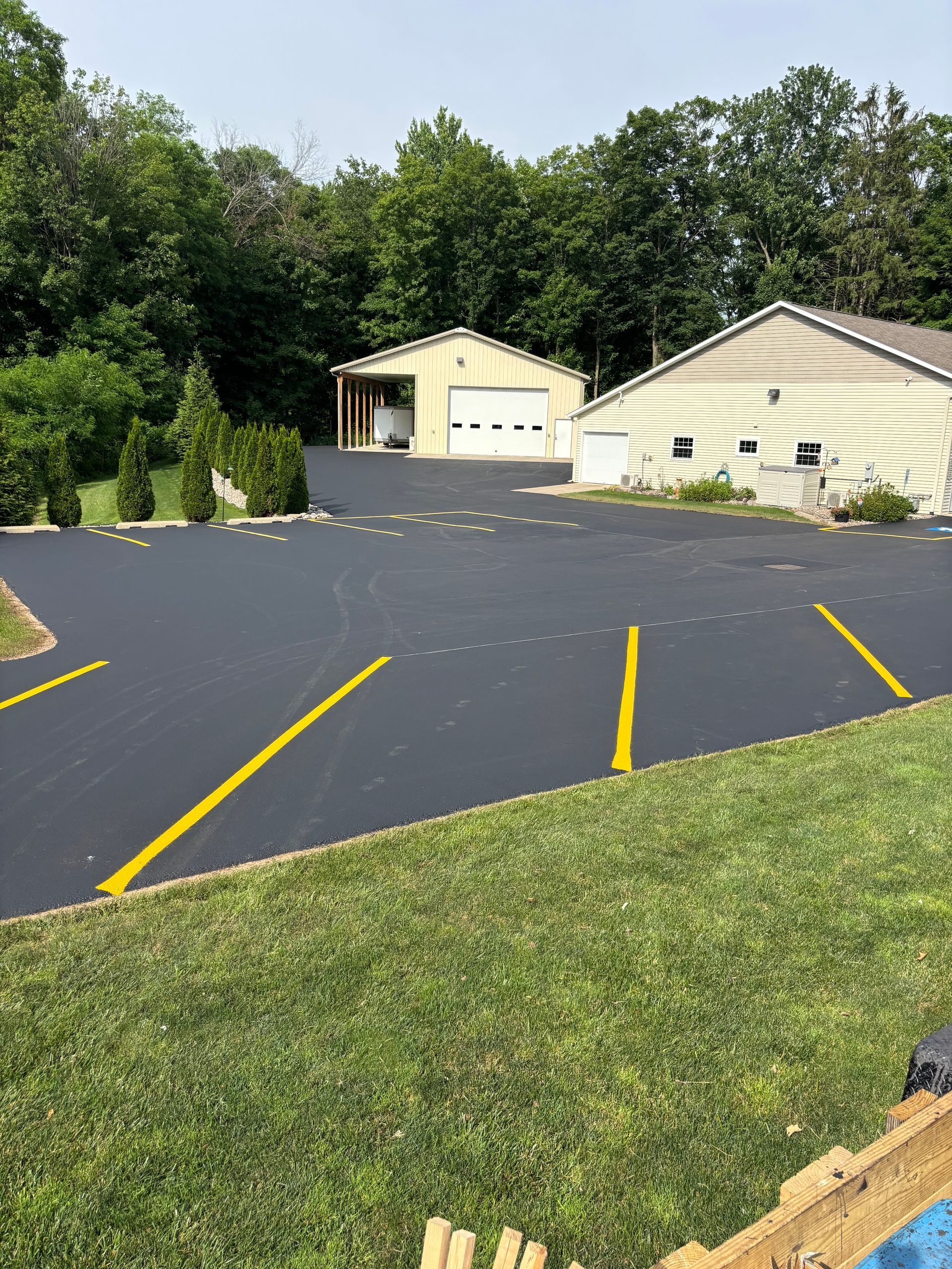A driveway with yellow lines and a house in the background.
