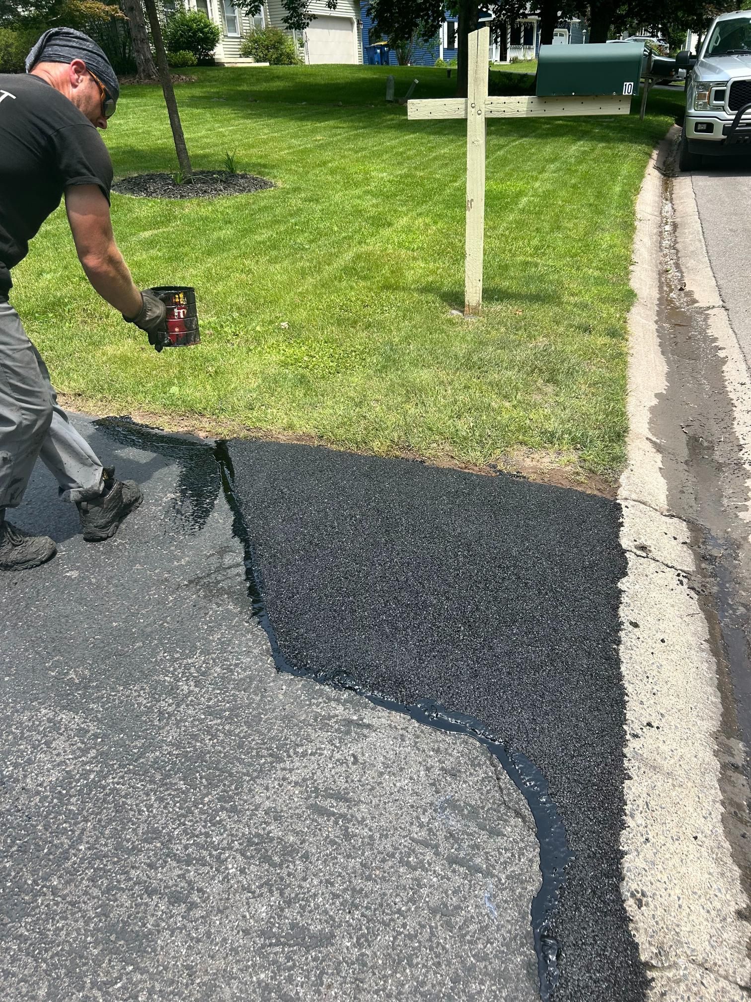 A man is spreading asphalt on the side of a road.