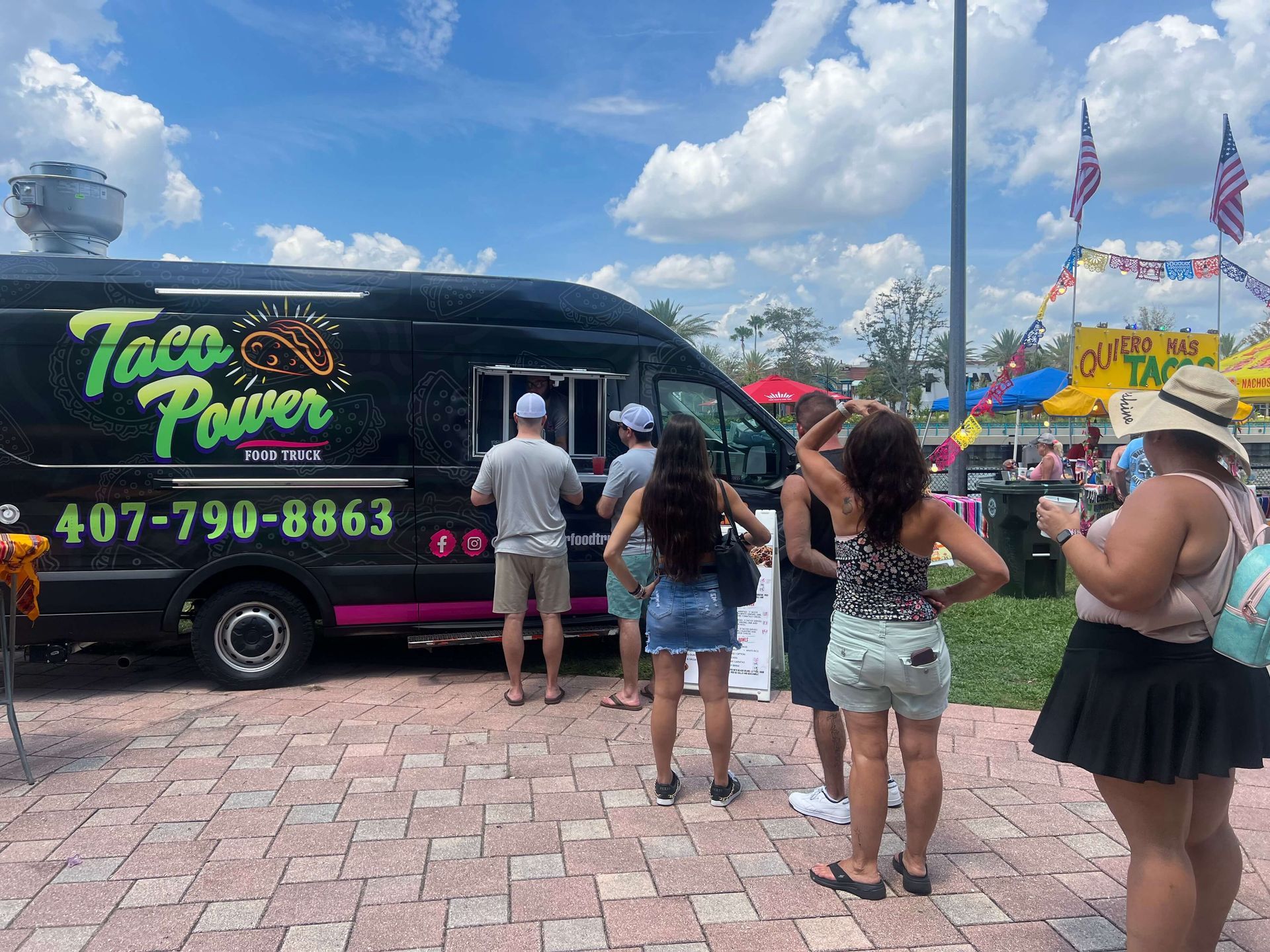 A group of people is standing in front of a taco truck.