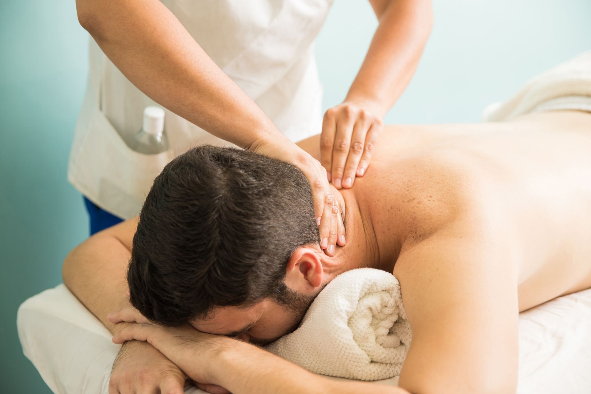 A man is laying on a massage table getting a massage from a woman.