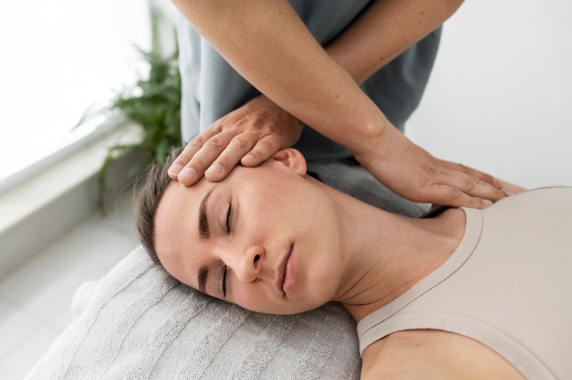 A woman is laying on a table getting a head massage.