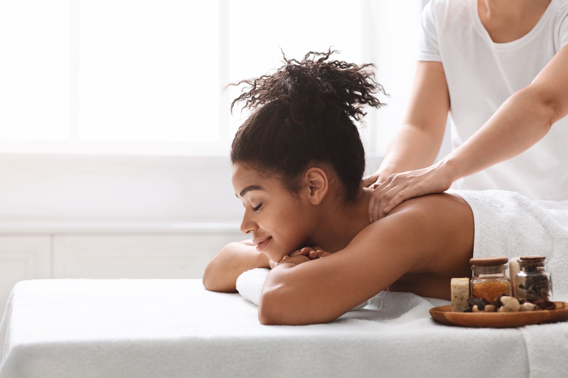 A woman is laying on a bed getting a massage.