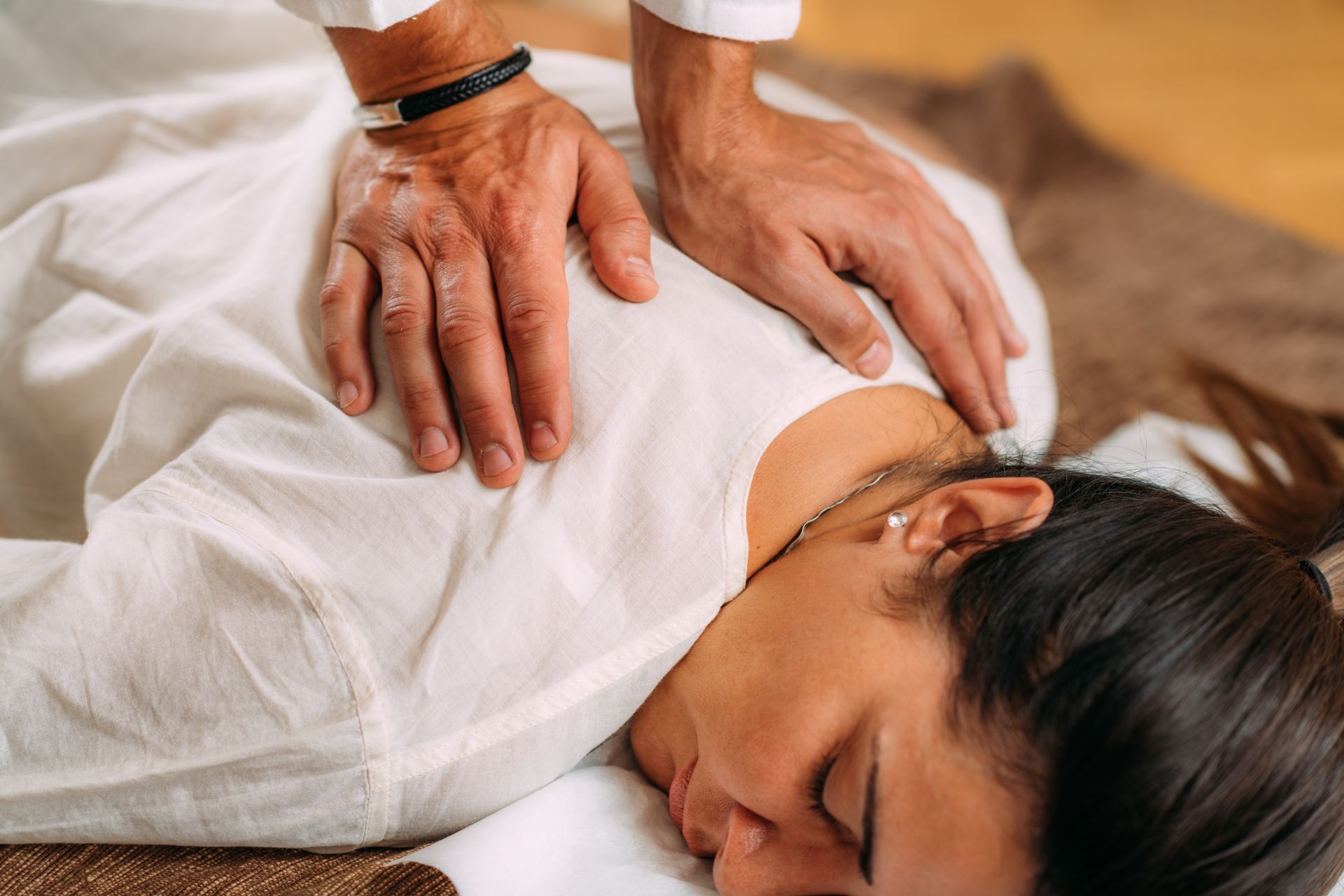 Person receiving a shoulder massage while lying face down on a blanket